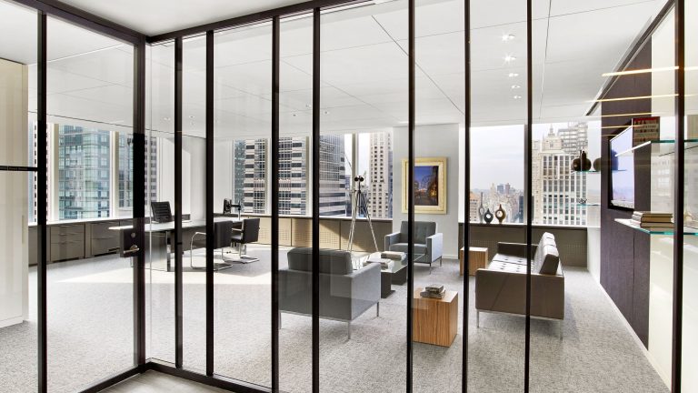 Modern office interior featuring Ultralight demountable glass partitions with a bespoke dark blue anodized aluminum finish.